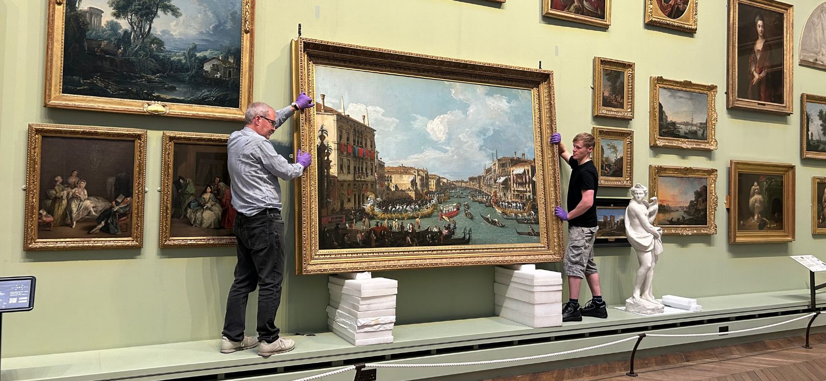 museum staff removing Regatta on the Grand Canal, Venice by Canaletto.