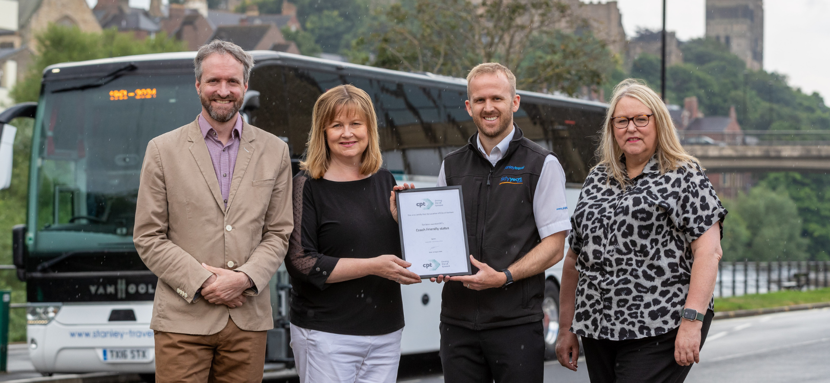 four people stood in front of a coach in Durham City Centre,