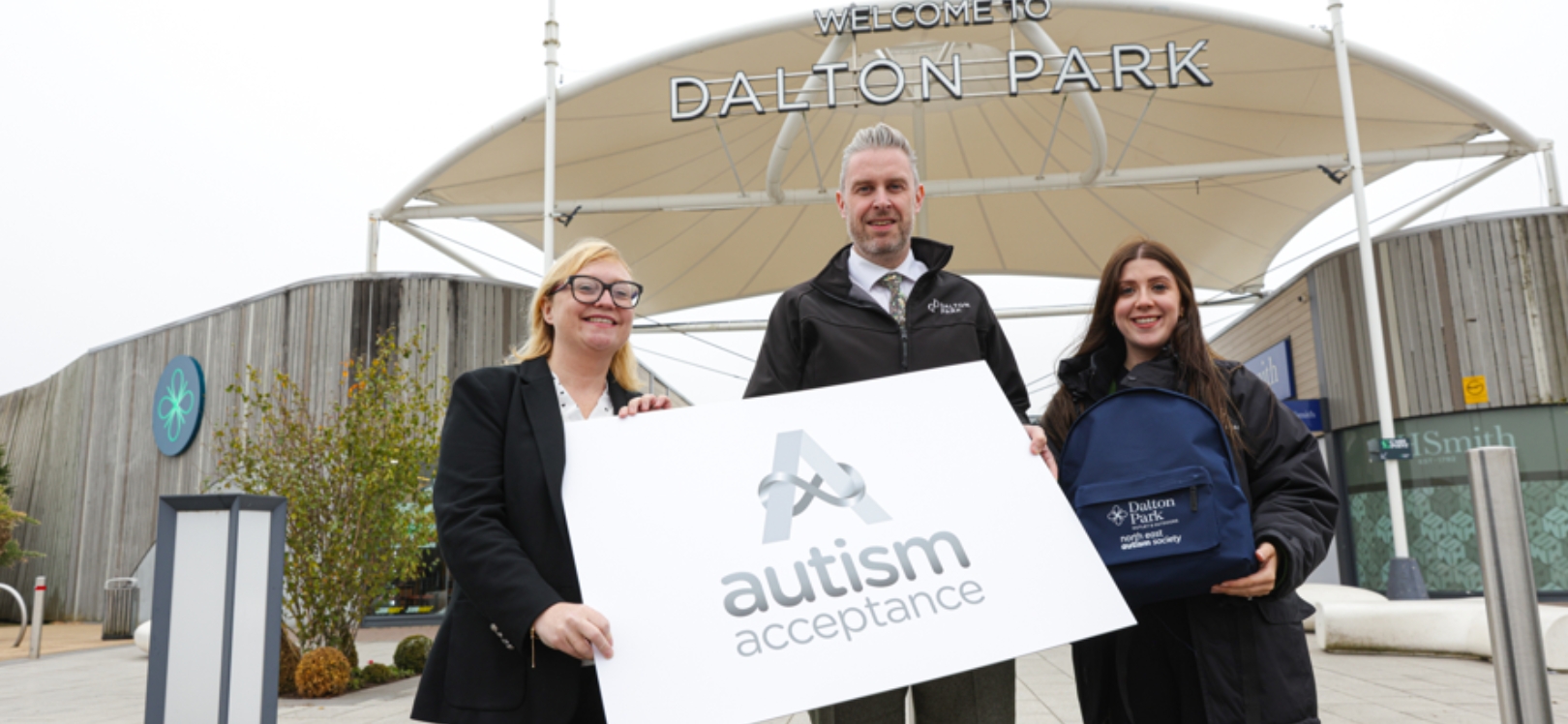 Three people holding an Autism Acceptance sign at Dalton Park