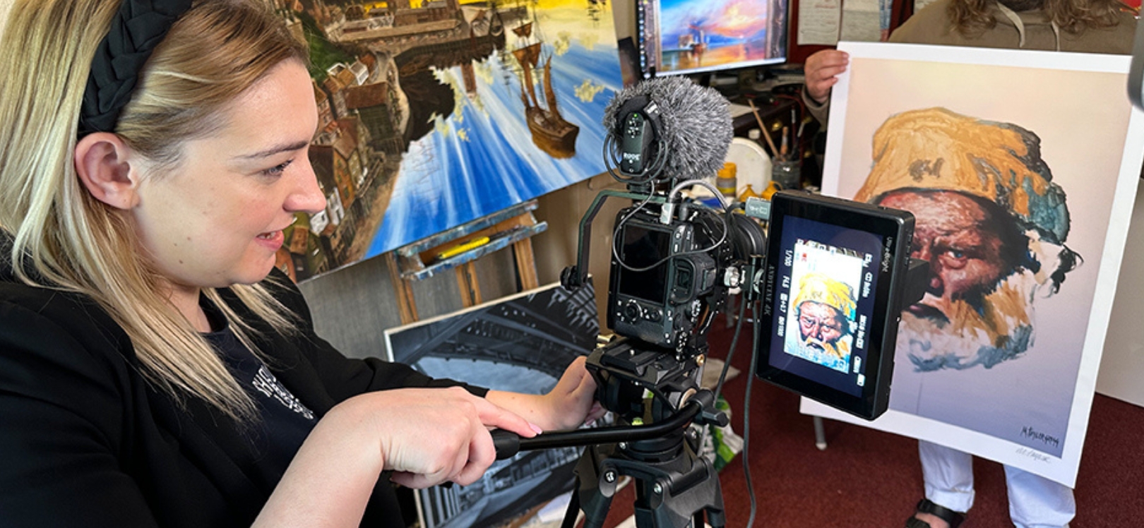 A woman holding a camera next to a painting